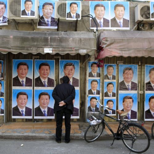 A-man-looks-at-a-building-covered-in-posters-of-Chinese-President-Xi-Jinping-in-Shanghai